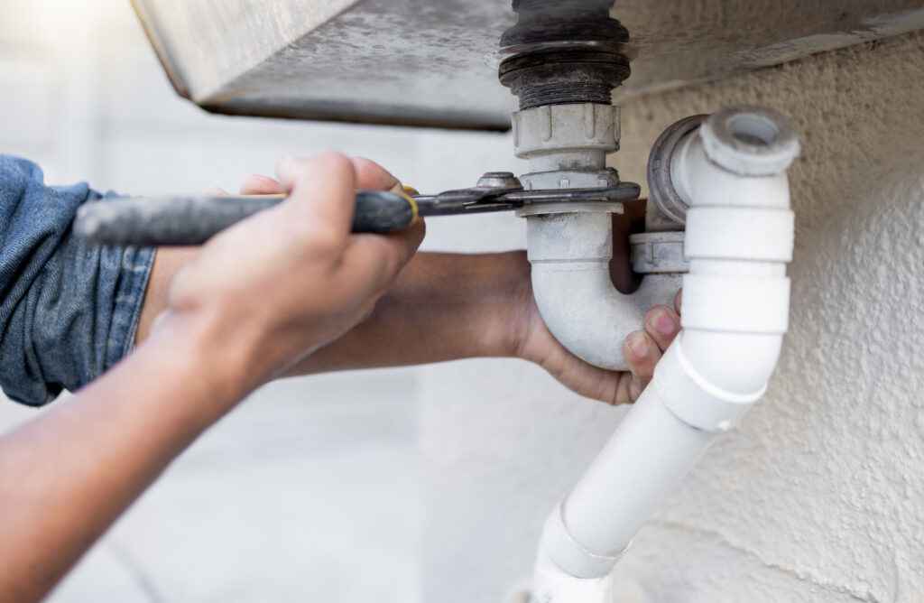 Hands, tool and pipe with a man plumber fixing a water system