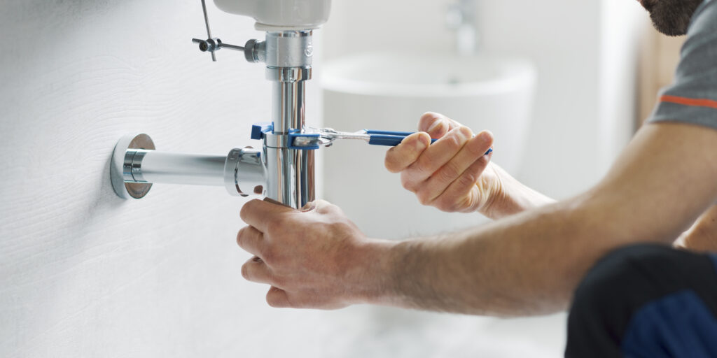 Professional plumber fixing a bathroom sink drain using water pump pliers