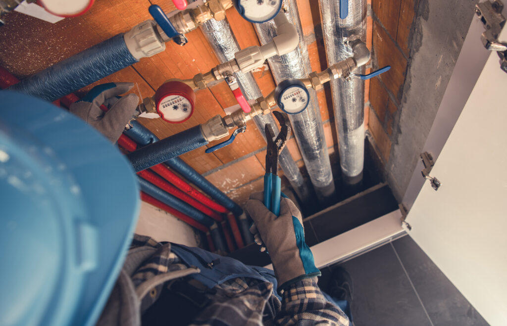 Aerial View of Plumber with Hydraulic Key Performing Hot and Cold Water Meters Service and Repair.